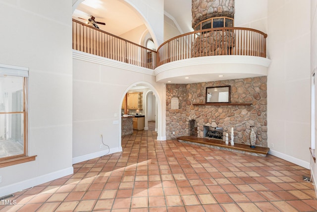 unfurnished living room featuring ceiling fan and a high ceiling