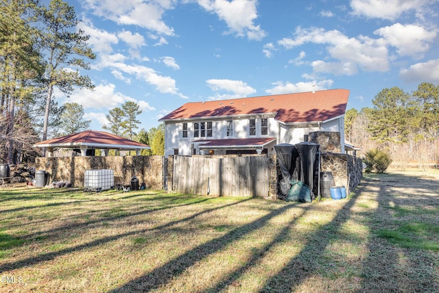 back of property featuring a gazebo, central air condition unit, and a lawn