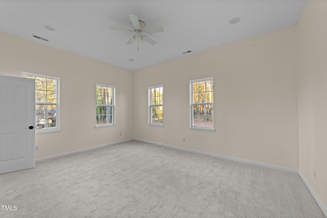 carpeted spare room featuring ceiling fan and plenty of natural light