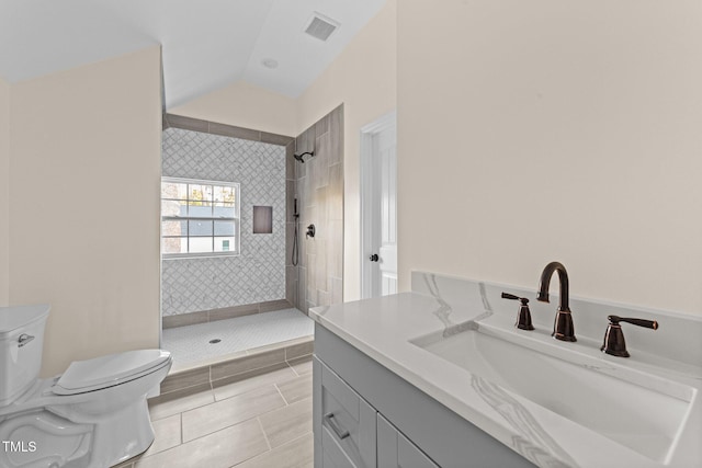 bathroom with vanity, tiled shower, tile patterned flooring, toilet, and lofted ceiling