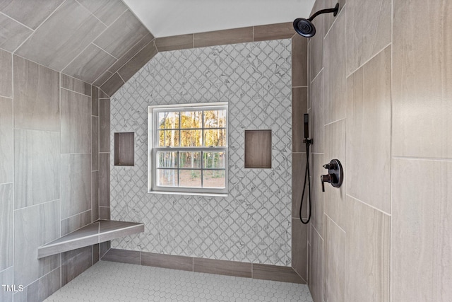 bathroom with a tile shower and lofted ceiling