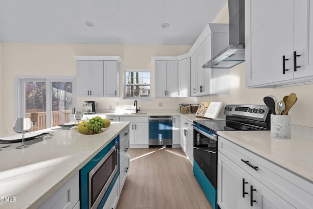 kitchen featuring white cabinets, sink, wall chimney range hood, and stainless steel appliances