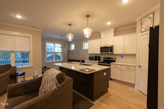 kitchen featuring an island with sink, sink, white cabinets, pendant lighting, and appliances with stainless steel finishes