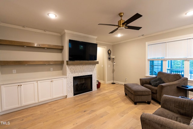 living room with ceiling fan, ornamental molding, light hardwood / wood-style flooring, and a tile fireplace