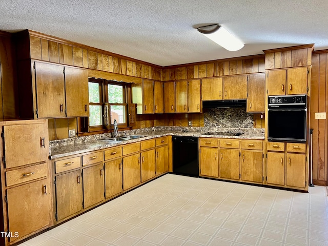 kitchen featuring wood walls, black appliances, sink, backsplash, and a textured ceiling