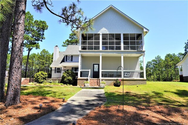 view of front of home with a sunroom, a front lawn, and covered porch