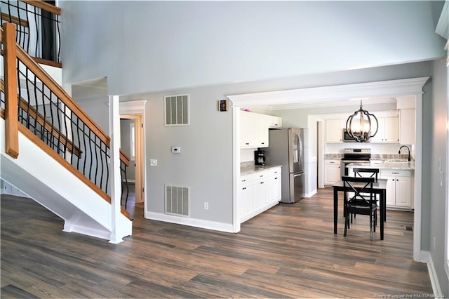 interior space featuring dark hardwood / wood-style floors, stainless steel appliances, white cabinets, sink, and decorative light fixtures