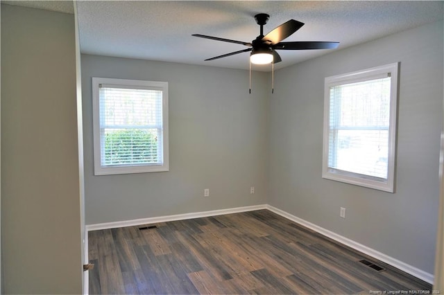 empty room with ceiling fan, a textured ceiling, dark hardwood / wood-style flooring, and a wealth of natural light