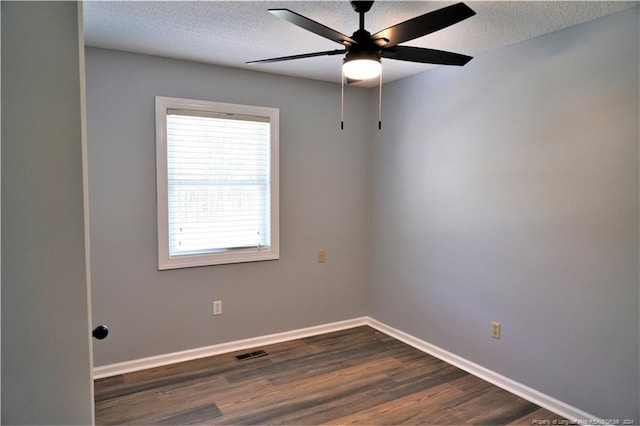 spare room featuring dark wood-type flooring, ceiling fan, and a textured ceiling