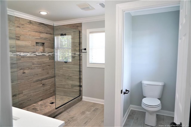 bathroom featuring ornamental molding, toilet, and tiled shower