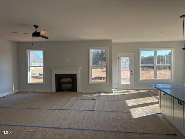 unfurnished living room featuring ceiling fan and a fireplace