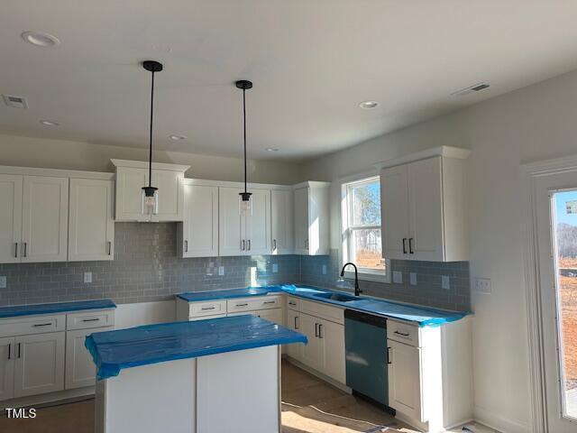 kitchen with dishwasher, a kitchen island, sink, white cabinetry, and hanging light fixtures