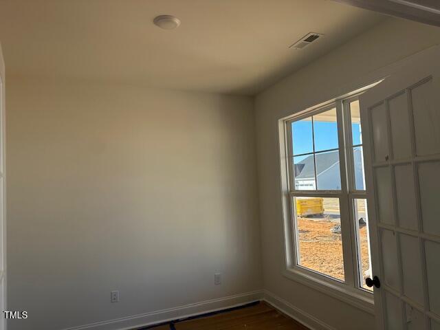 empty room featuring a healthy amount of sunlight and dark hardwood / wood-style floors