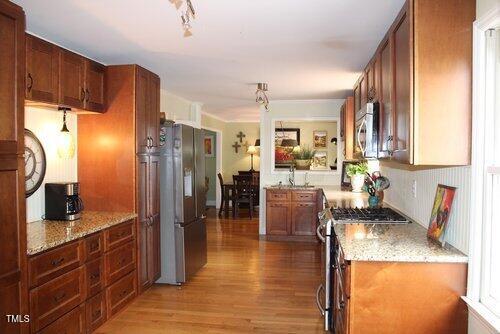 kitchen featuring light stone countertops, appliances with stainless steel finishes, and light wood-type flooring