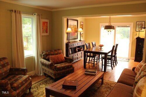 living room with crown molding, a notable chandelier, and light wood-type flooring