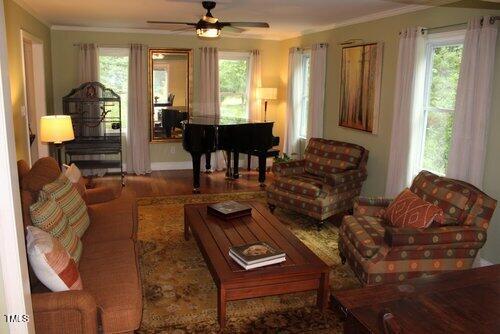 living room with ceiling fan, plenty of natural light, and ornamental molding