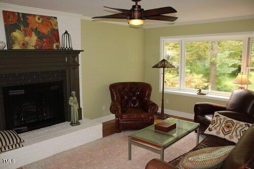 sitting room featuring ceiling fan, light colored carpet, a fireplace, and crown molding