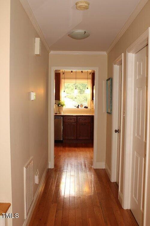 hallway with ornamental molding and hardwood / wood-style flooring