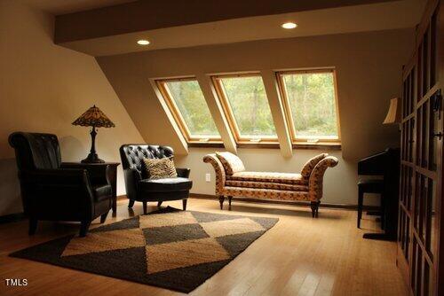 sitting room with beamed ceiling, a skylight, and light wood-type flooring