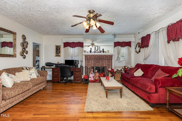 living area with hardwood / wood-style floors, plenty of natural light, a ceiling fan, and a textured ceiling