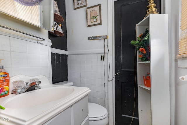 bathroom featuring tile walls, a wainscoted wall, vanity, and toilet