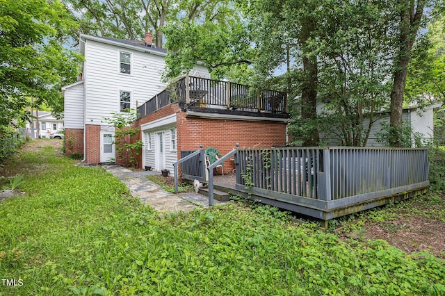 back of property featuring a yard, a deck, and a chimney
