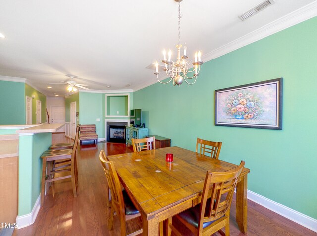 dining area featuring ornamental molding, dark hardwood / wood-style floors, and ceiling fan with notable chandelier