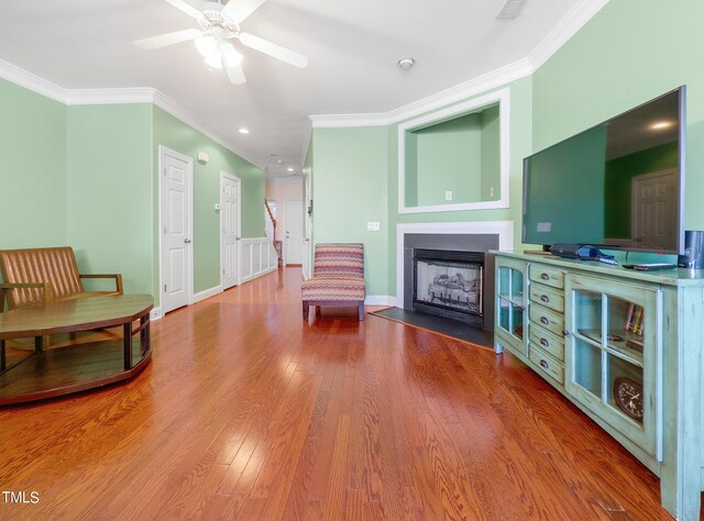 living area featuring ceiling fan, wood-type flooring, and ornamental molding