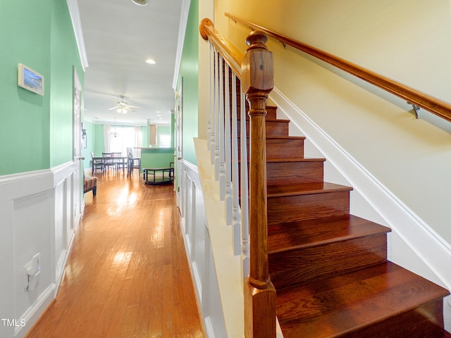 stairway with ceiling fan, ornamental molding, and hardwood / wood-style floors