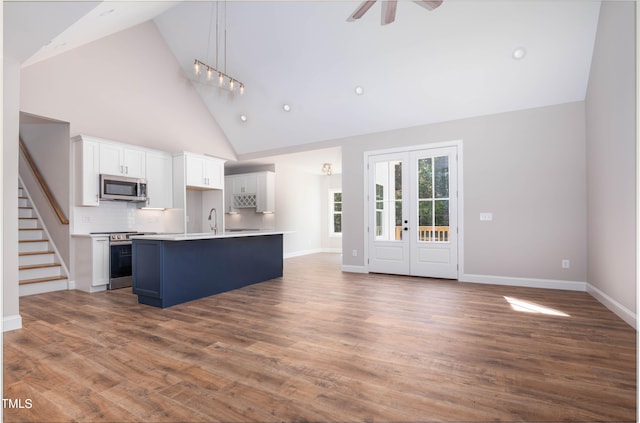 kitchen with white cabinets, a kitchen island with sink, high vaulted ceiling, decorative light fixtures, and stainless steel appliances