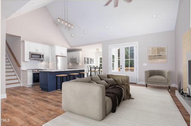 living room with light hardwood / wood-style flooring, french doors, high vaulted ceiling, and ceiling fan