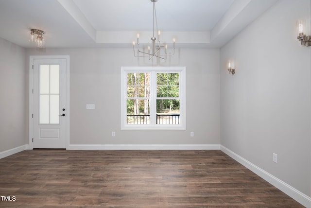 unfurnished dining area featuring dark wood-type flooring, a notable chandelier, and a raised ceiling