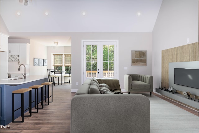 living room with french doors, vaulted ceiling, hardwood / wood-style flooring, and sink