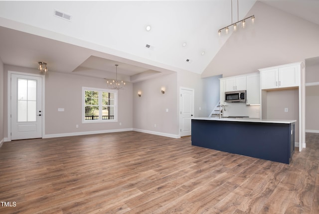 kitchen with white cabinets, a kitchen island with sink, hardwood / wood-style floors, and pendant lighting