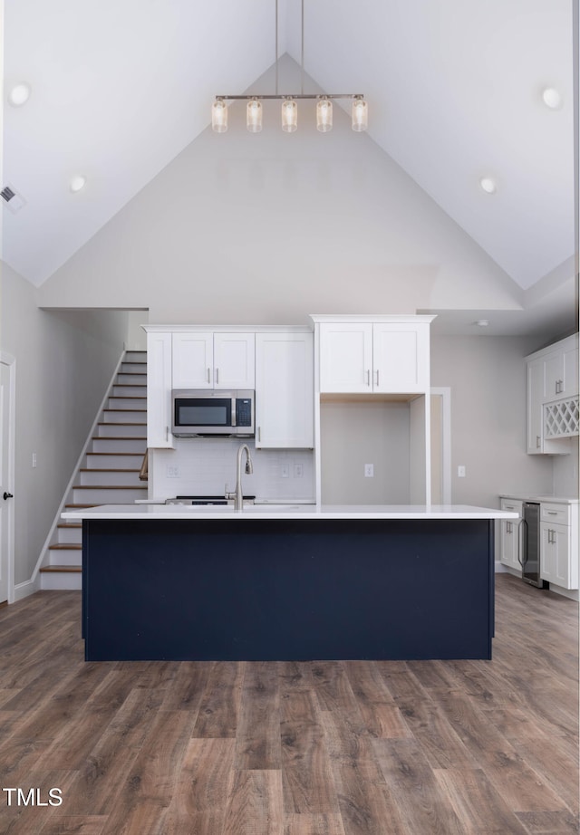 kitchen featuring white cabinets, dark wood-type flooring, and an island with sink