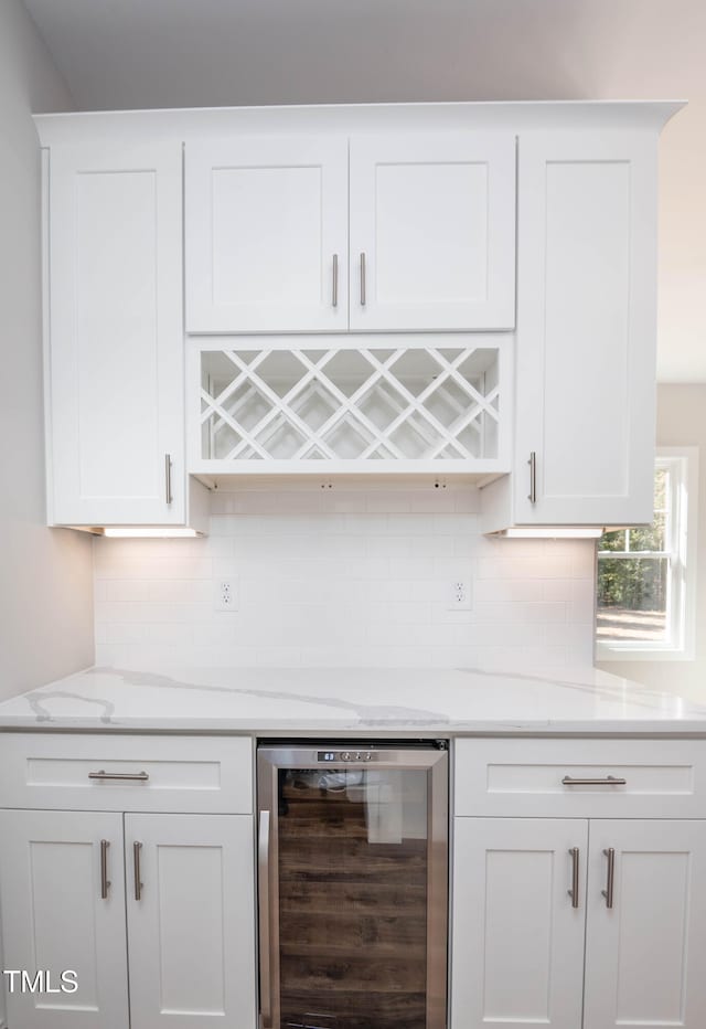 bar featuring light stone countertops, decorative backsplash, white cabinets, and beverage cooler