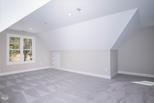 bonus room with vaulted ceiling and light carpet