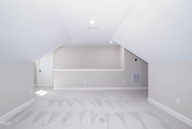 additional living space featuring vaulted ceiling and light carpet