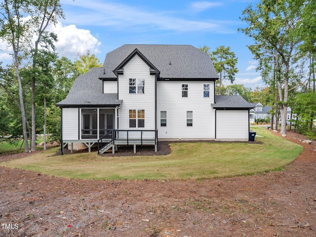 back of house featuring a sunroom, a deck, and a lawn