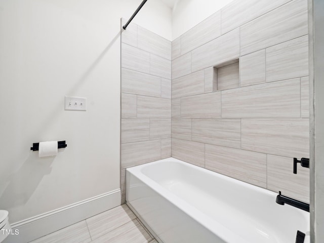 bathroom with tile patterned floors, tiled shower / bath combo, and toilet