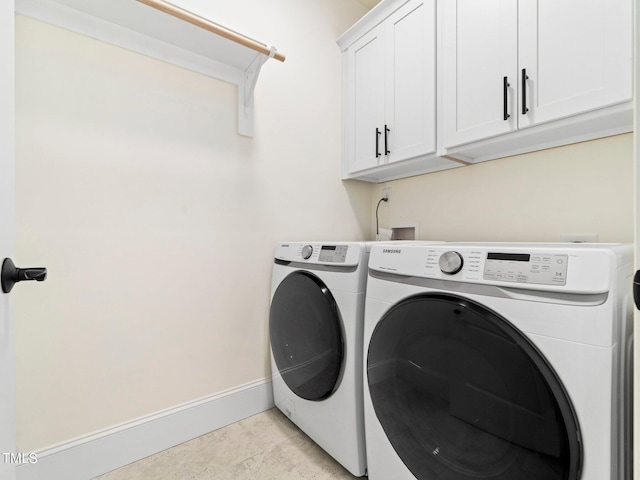 clothes washing area with washing machine and dryer, light tile patterned floors, and cabinets