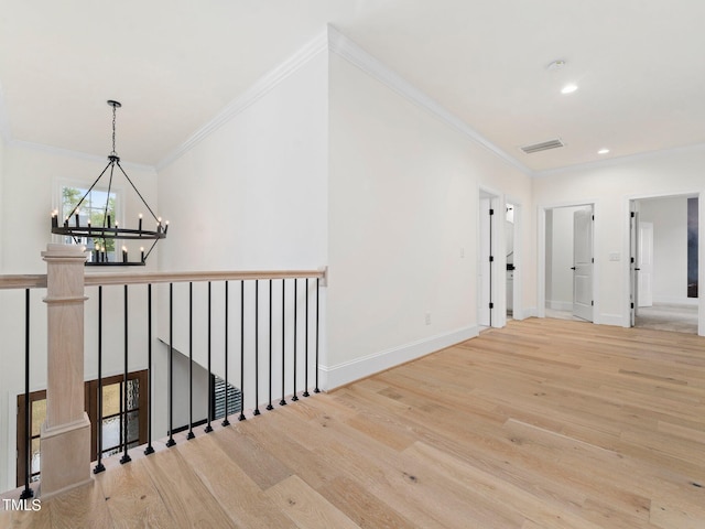 corridor featuring crown molding, a chandelier, and light wood-type flooring