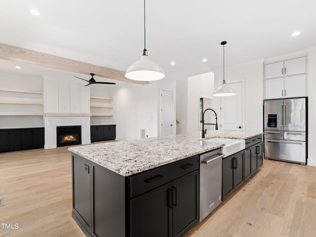 kitchen featuring sink, an island with sink, stainless steel appliances, and decorative light fixtures