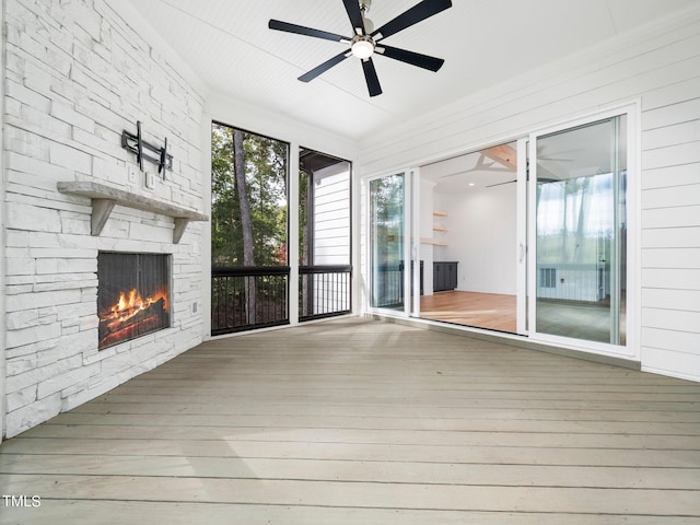 interior space with ceiling fan and a stone fireplace