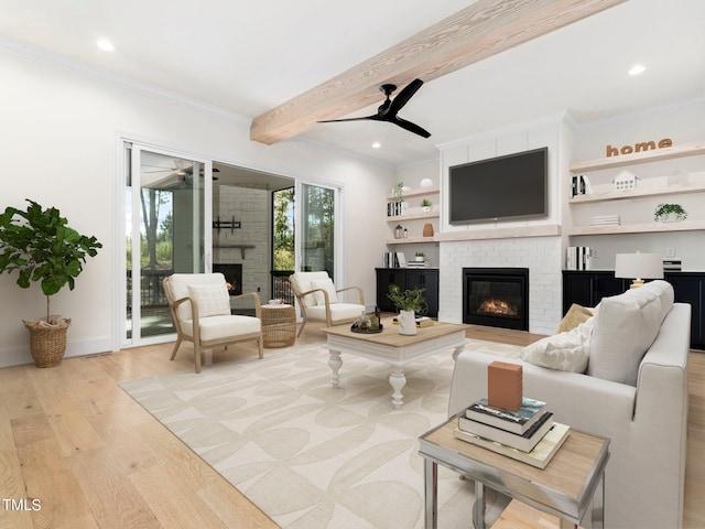 living room featuring crown molding, a brick fireplace, ceiling fan, light wood-type flooring, and beam ceiling