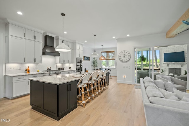 kitchen with open floor plan, premium range hood, light wood finished floors, and decorative backsplash