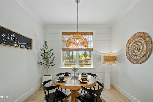 dining area featuring baseboards, light wood-type flooring, and crown molding