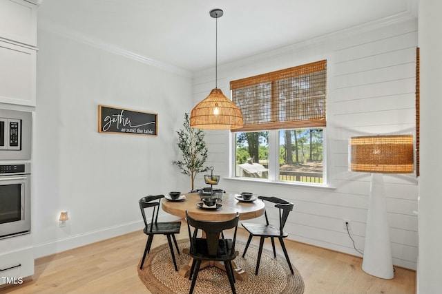 dining room with light wood-type flooring, crown molding, and baseboards