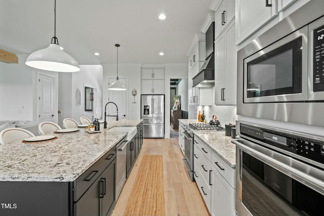 kitchen with crown molding, backsplash, light wood-style flooring, appliances with stainless steel finishes, and a sink