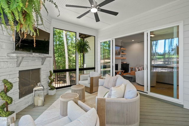 sunroom with a stone fireplace and a ceiling fan